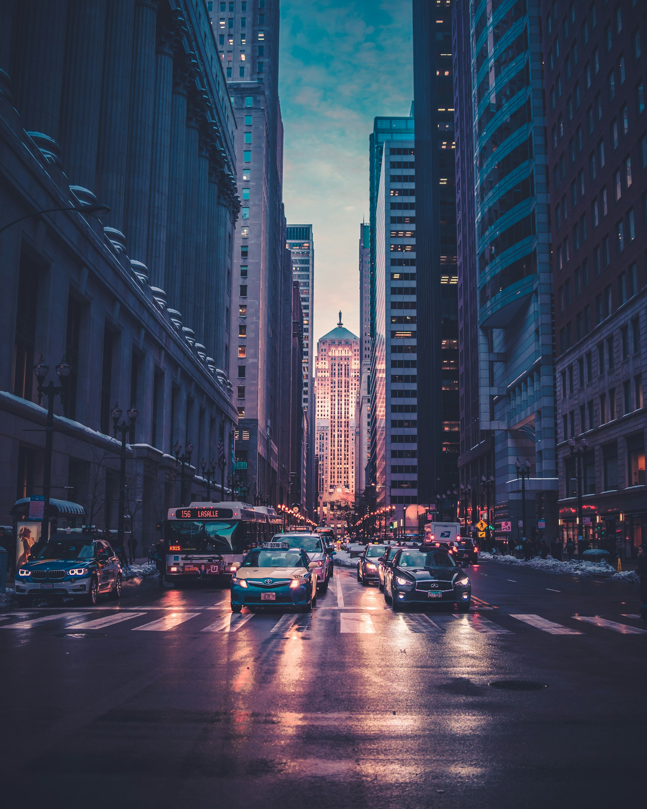 A lively New York street framed by tall buildings at dusk